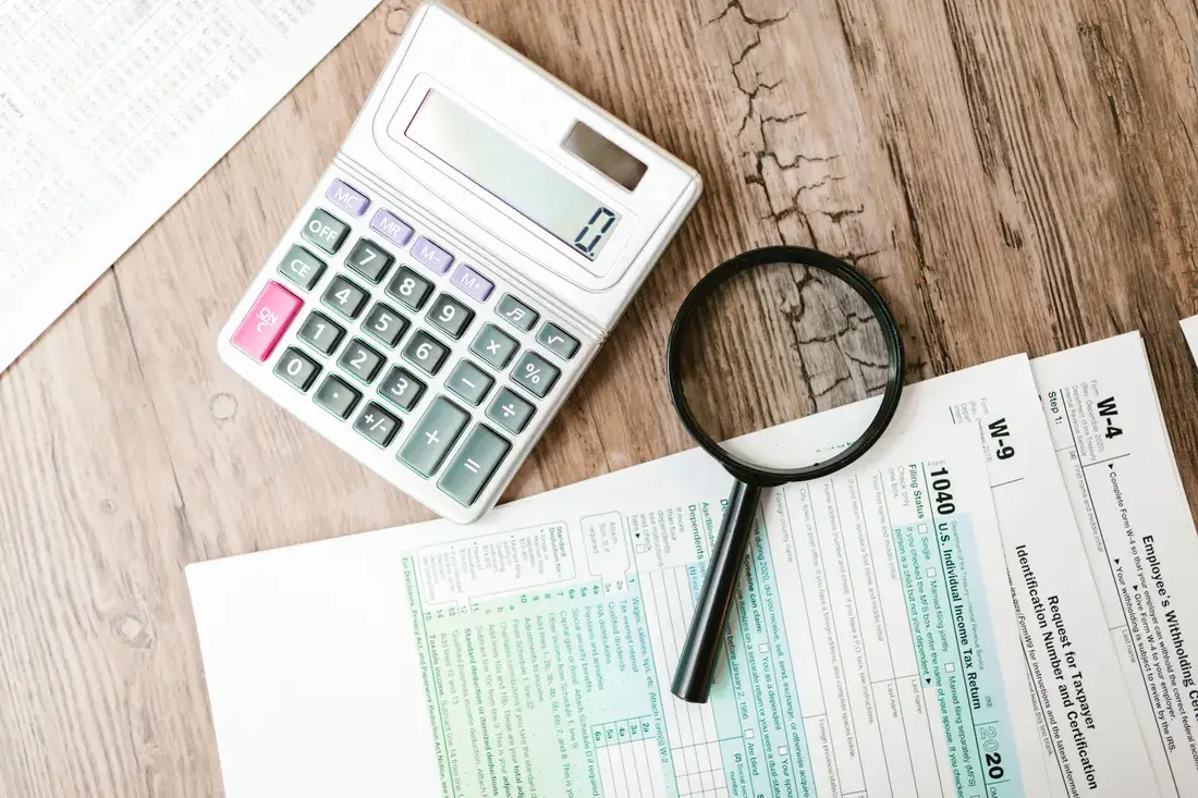 A calculator and magnifying glass on federal tax forms